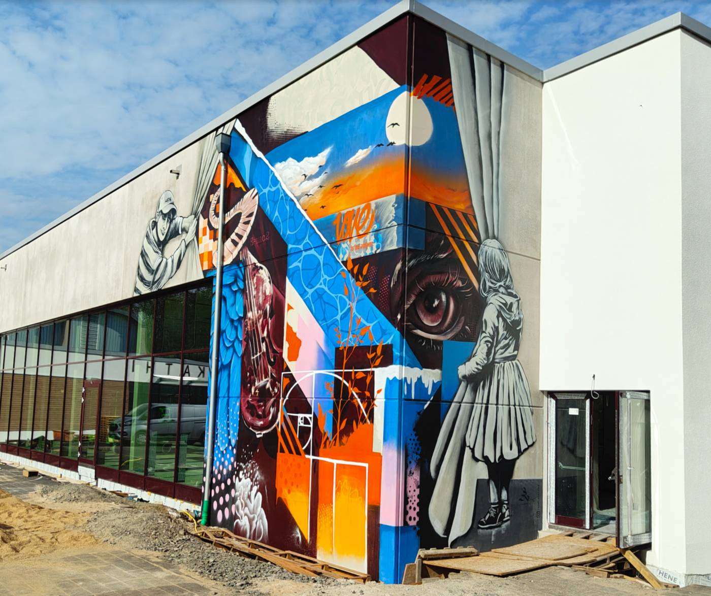 Großflächig gestaltete Fassade eines Gewerbebaus in Blau, Orange und Weiß